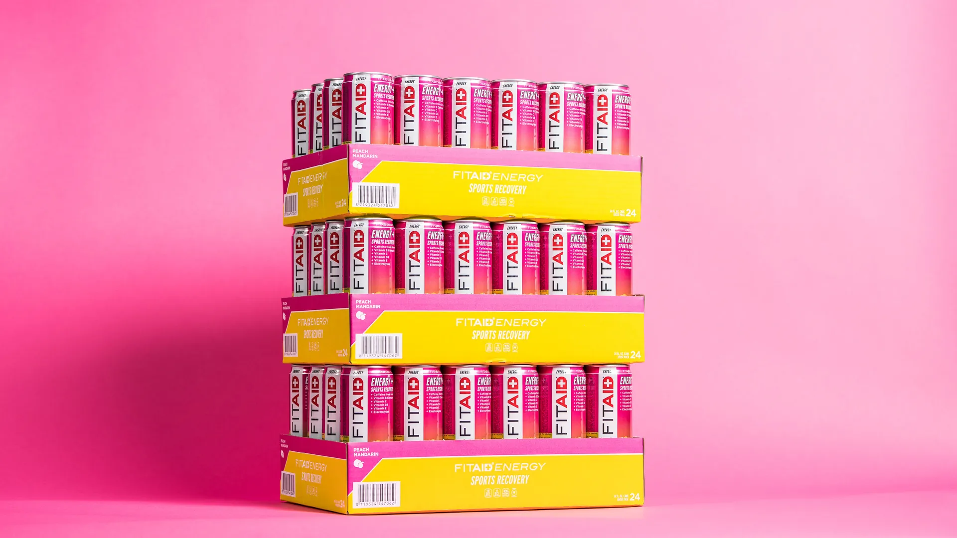 Trays FITAID sportdrank gestapeld tegen een roze achtergrond