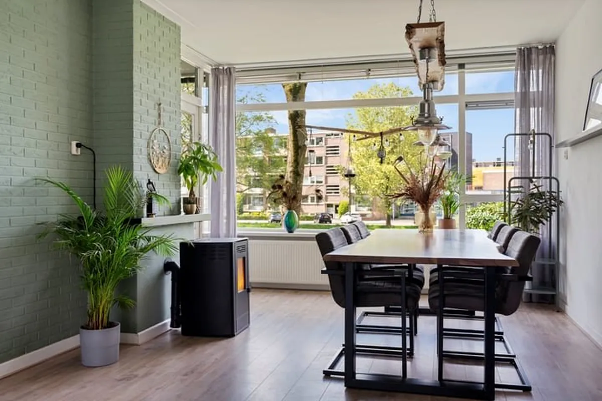 Eetkamer met groene wand en uitzicht op straat