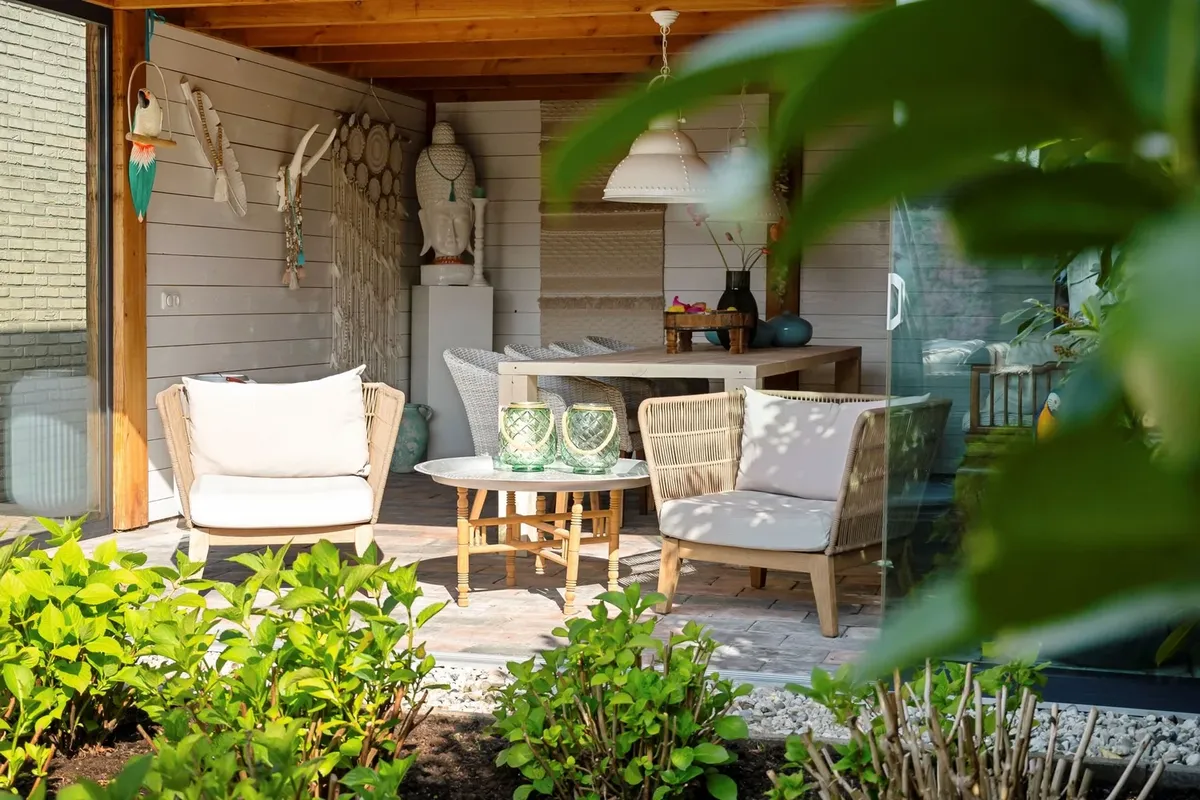 Overdekt terras met rieten stoelen en beplanting