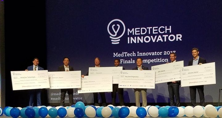 MedTech Innovator 2017 finalists holding oversized award checks on stage at the Finals Competition