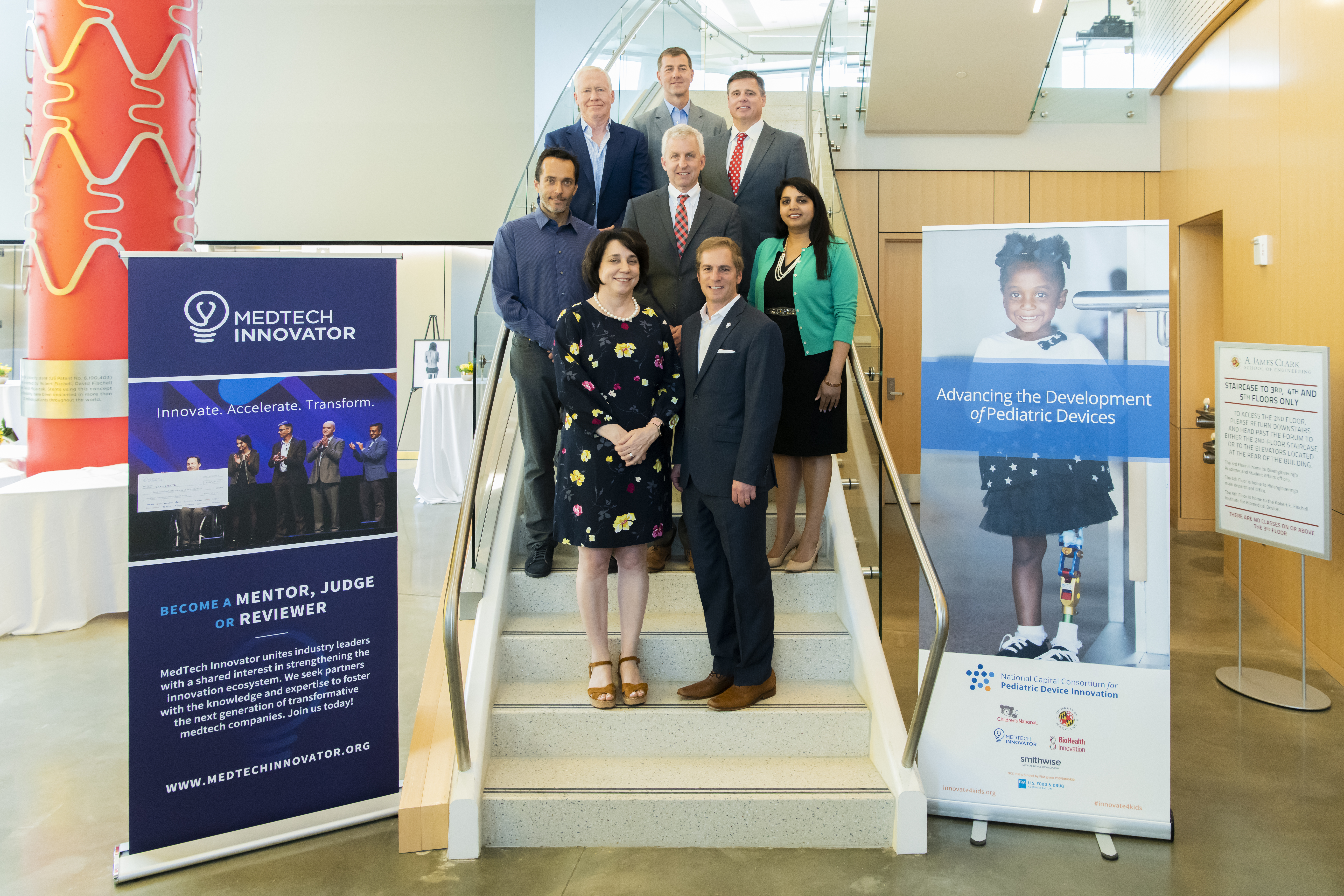 NCC-PDI and MedTech Innovator group photo on a staircase between event banners