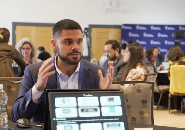 A founder pitching from a laptop at an MTI pitch table