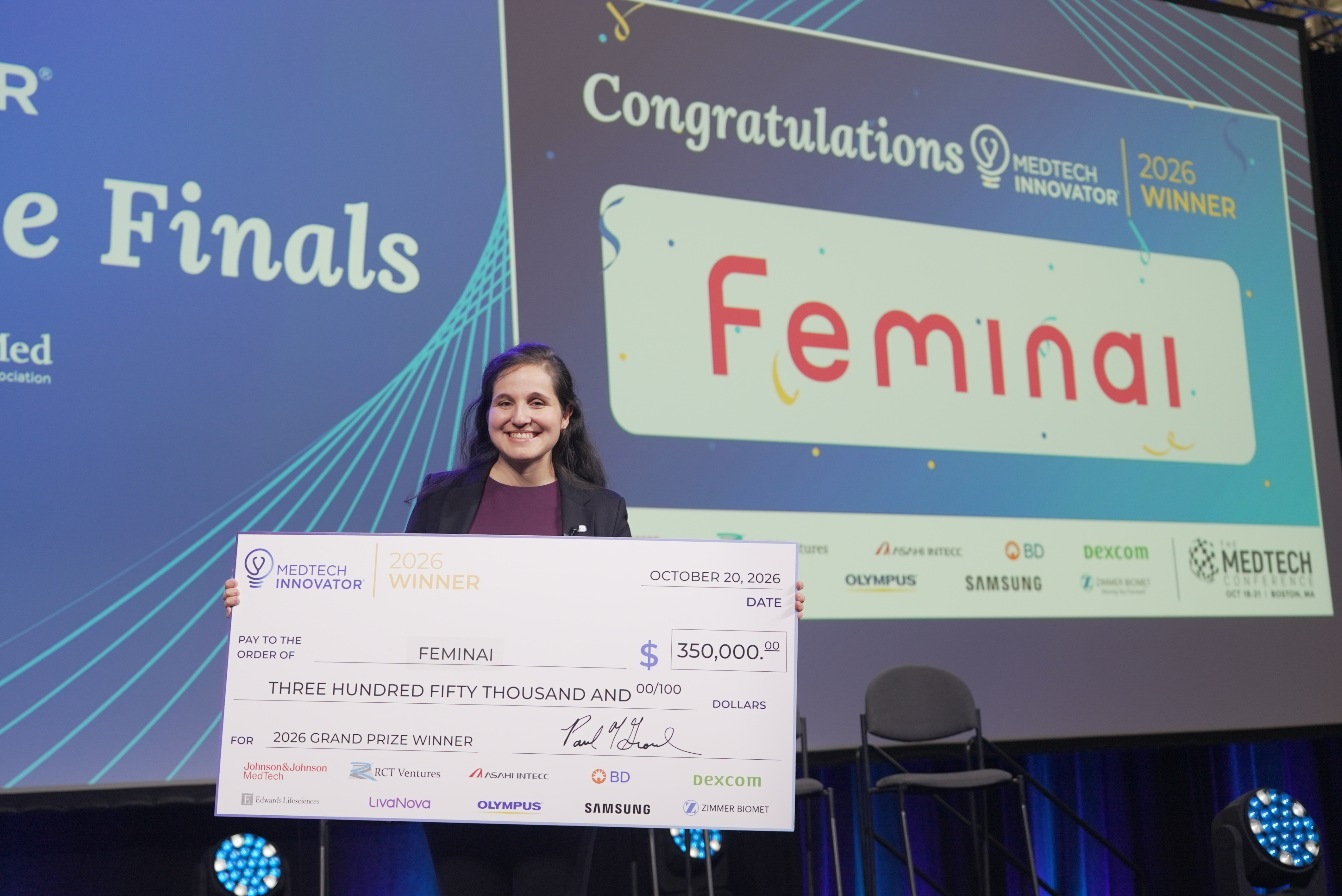 Feminai co-founder and CEO Dr. Karny Ilan holds the $350,000 MedTech Innovator 2026 Grand Prize check on stage at The MedTech Conference in Boston