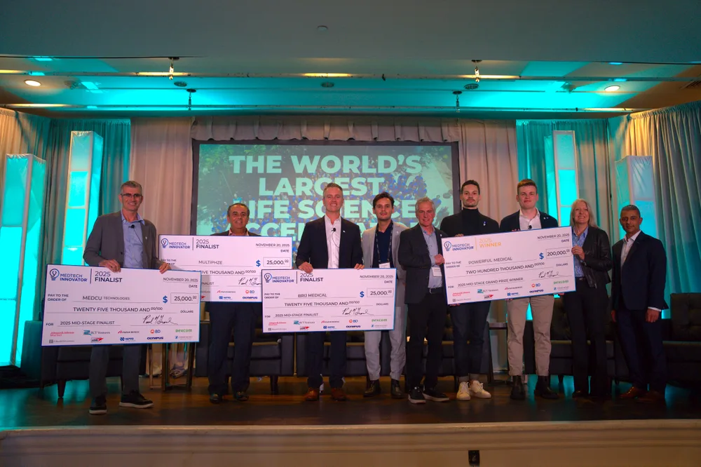 Finalists and judges holding prize cheques on stage at the 2025 MedTech Innovator Mid-Stage Finals