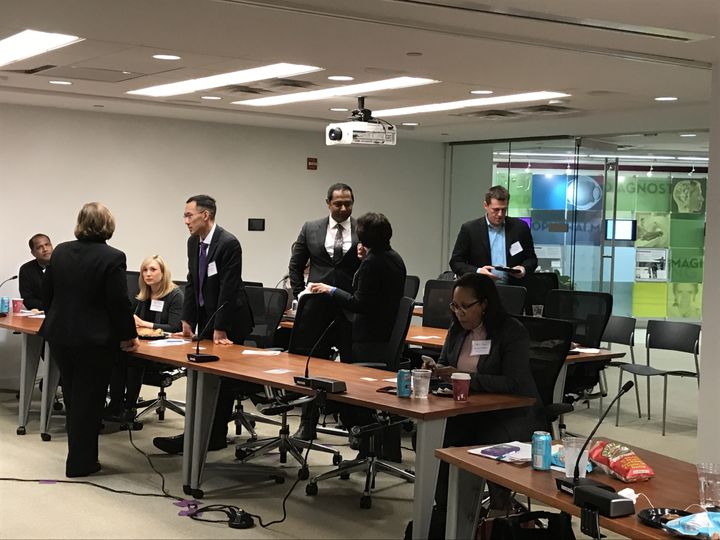 Judges and attendees mingling around conference tables at the MedTech Innovator D.C. pitch event