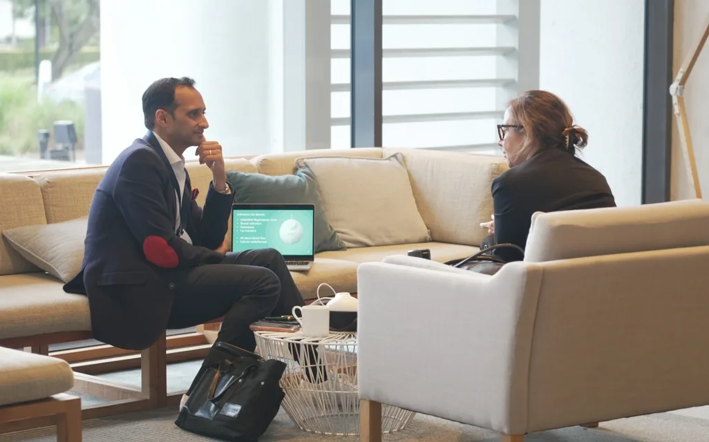 A founder and a mentor in a one-on-one conversation in a lounge, with a laptop presentation open between them