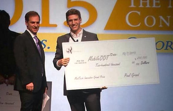 Paul Grand presenting MobileODT with the $200,000 MedTech Innovator 2015 Grand Prize check on stage at AdvaMed 2015