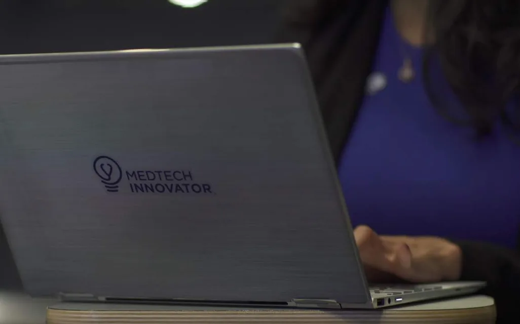 A founder working on a laptop with the MedTech Innovator logo on its lid