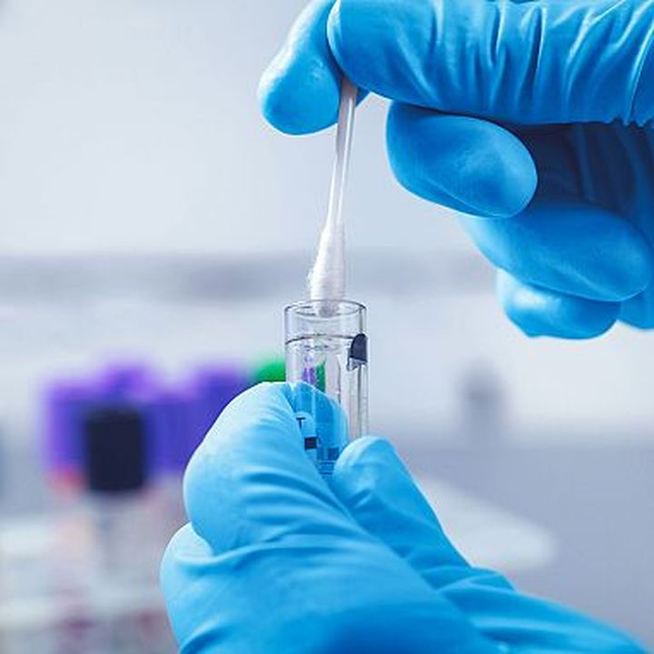 Gloved hand holding a laboratory sample tube