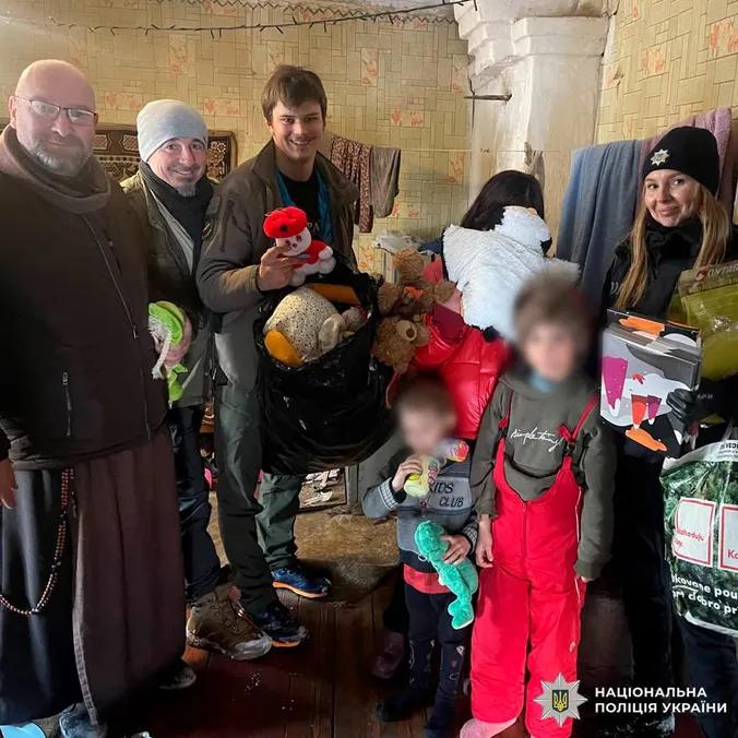 Hjælpere og en politibetjent deler bamser og legetøj ud til børn i et slidt hjem i Ukraine.
