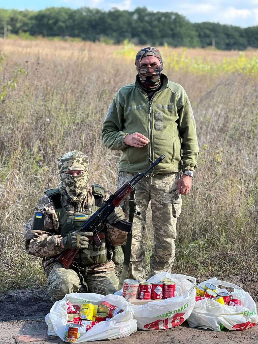 To ukrainske soldater i camouflage på en mark med poser fyldt med konserves leveret som nødhjælp fra Danmark