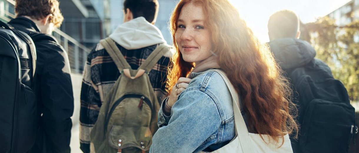 Auszubildende mit Rucksack lächelt über die Schulter