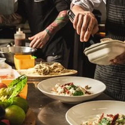 Köche richten Pastagerichte in tiefen Tellern an