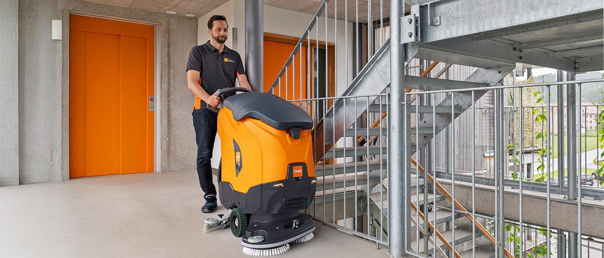 Mitarbeiter mit TASKI-Scheuersaugmaschine in einem Treppenhaus