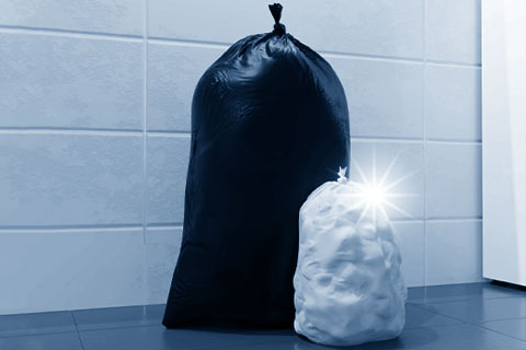 Schwarzer und weißer Müllsack vor Fliesenwand