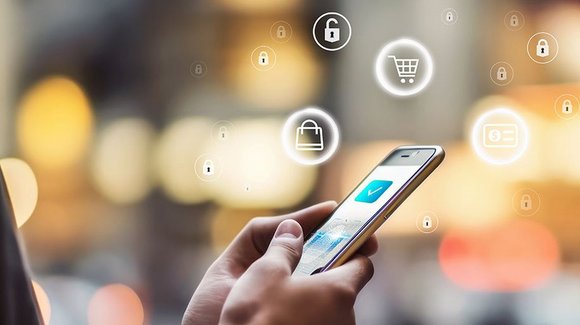 Hand am Smartphone, schwebende Symbole für Einkaufswagen und Schloss