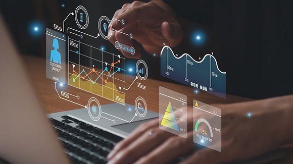 Hände an einem Laptop, eingeblendete Diagramme und Kennzahlen