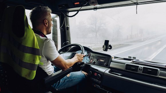 Fahrer in Warnweste am Steuer eines LKW