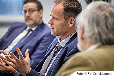 Drei Männer im Gespräch, einer gestikuliert