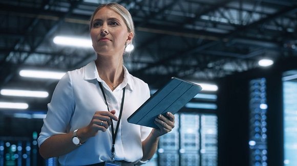 Frau mit Tablet zwischen Serverschränken