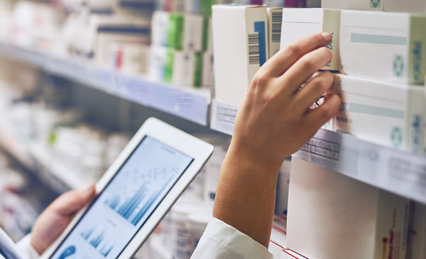 Hand entnimmt eine Medikamentenpackung, Tablet mit Diagrammen