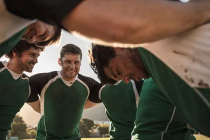 Rugbyteam in grünen Trikots im Mannschaftskreis