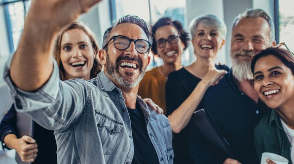 Gruppe lachender Kolleginnen und Kollegen beim Selfie