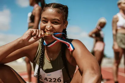 Sportlerin auf der Laufbahn beißt in ihre Medaille