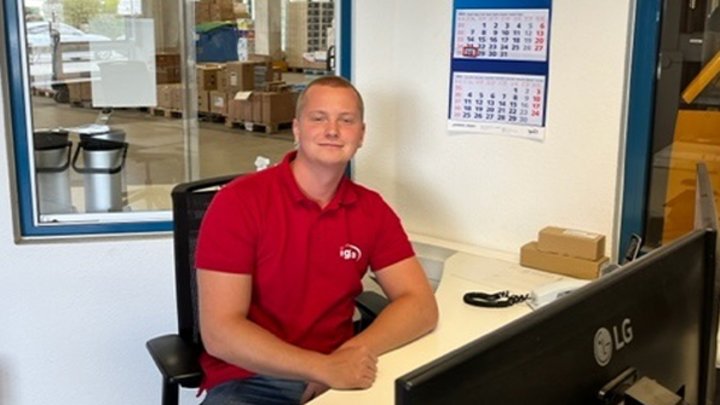 Mitarbeiter im roten Polo am Schreibtisch im Lagerbüro