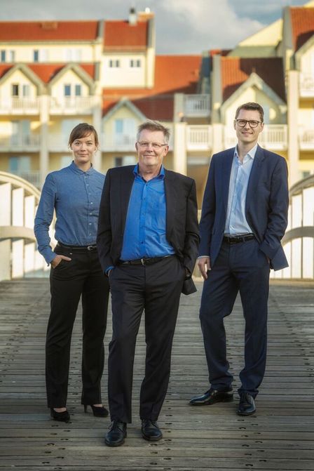 Drei Personen in Businesskleidung auf einer Holzbrücke