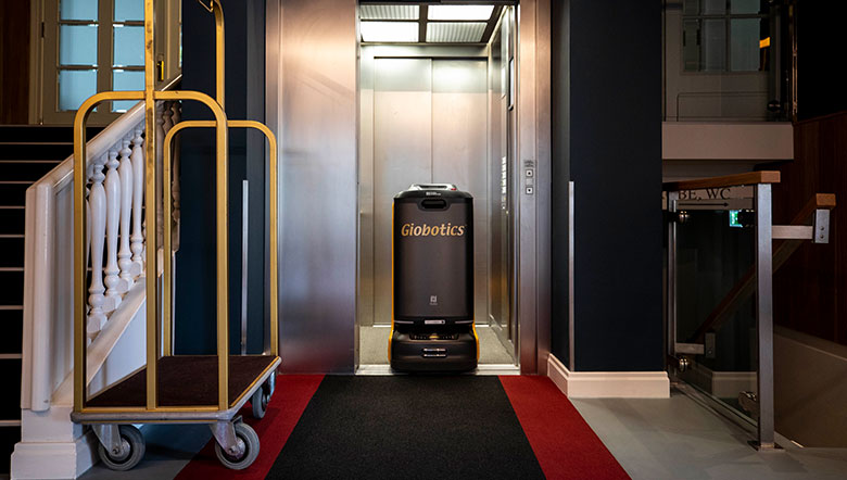 Serviceroboter im Hotelaufzug neben einem Gepäckwagen