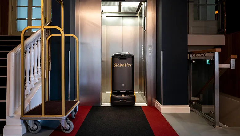 Serviceroboter im Hotelaufzug neben einem Gepäckwagen