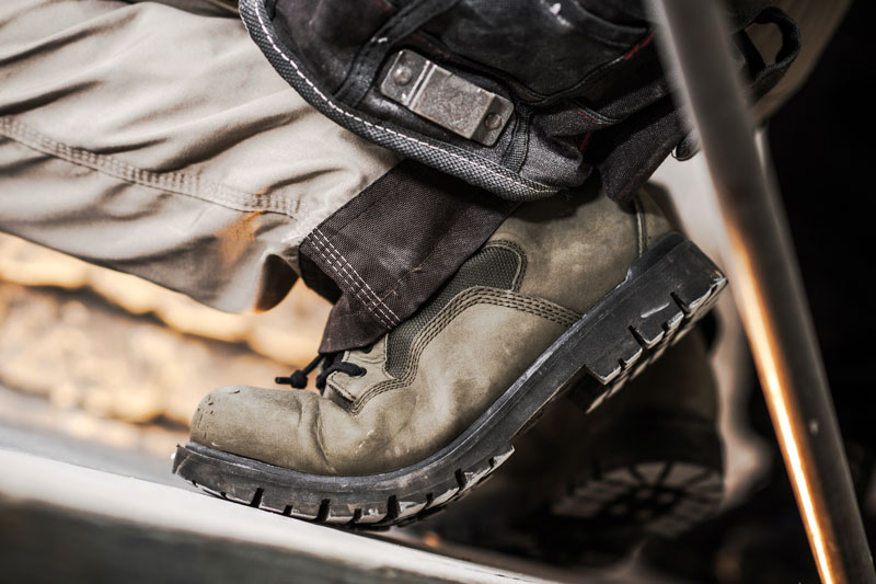 Abgenutzter Sicherheitsschuh auf einer Metallstufe