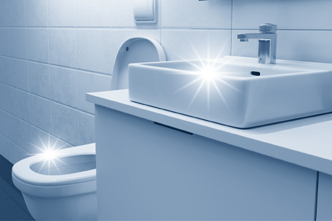 Waschbecken und WC in gefliestem Sanitärraum
