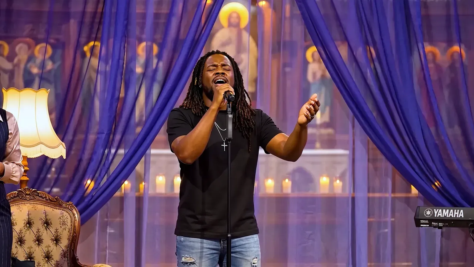 A man in a black t-shirt singing passionately in a candlelit church, painted saints and a keyboard behind