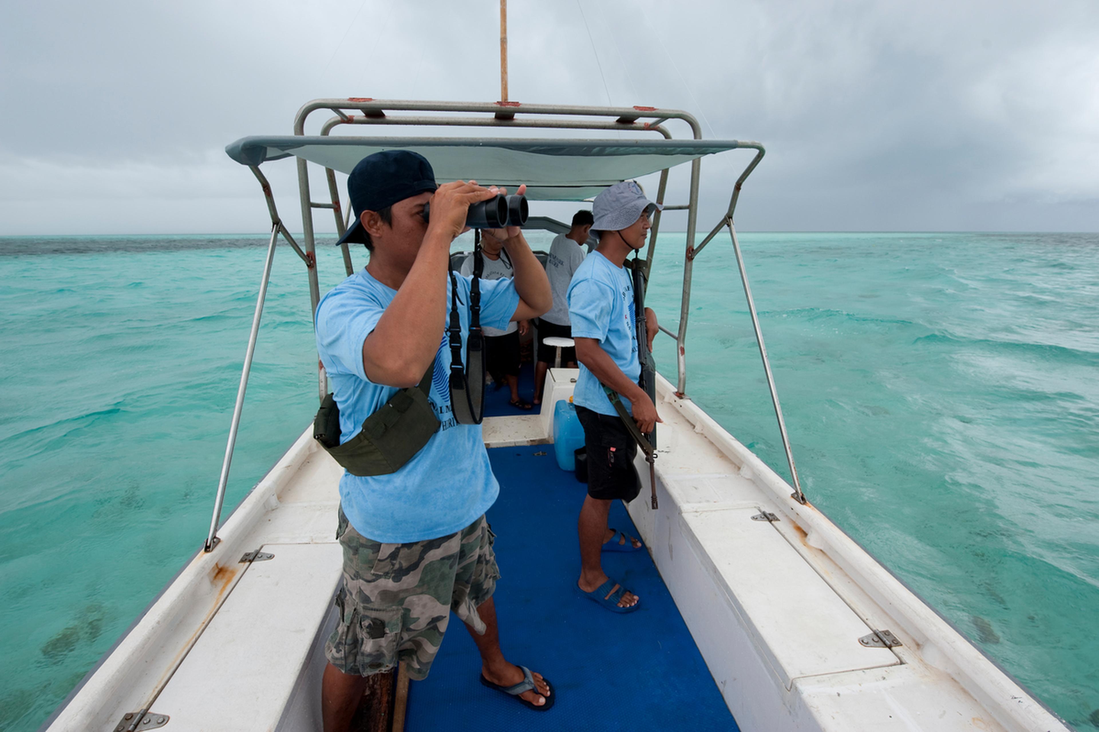 man met verrekijker kijkt vanuit boot uit op zee