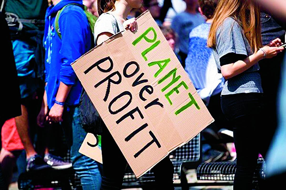 Vrouw met bord in de hand met de tekst 'Planet over profit'