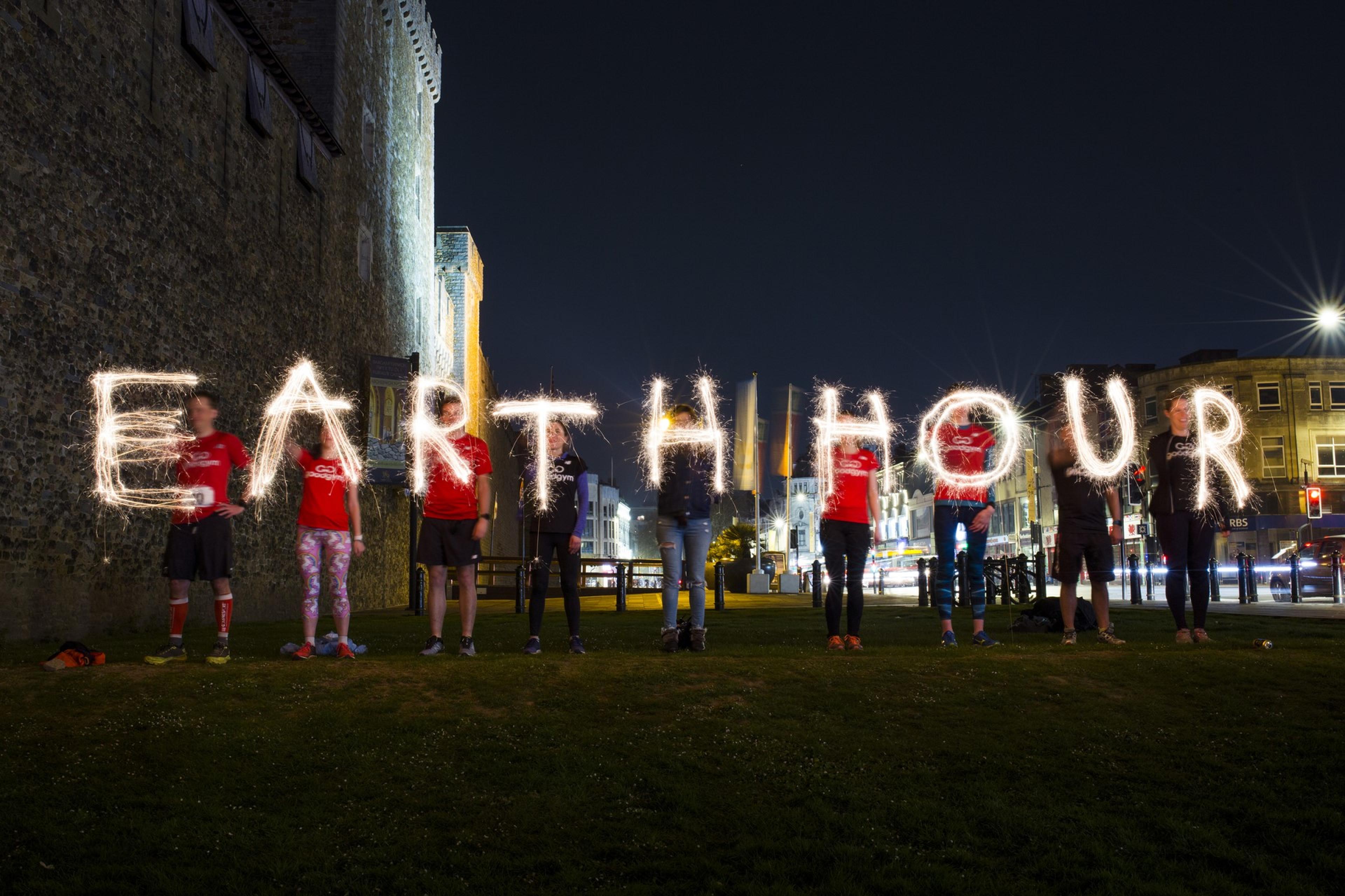 Groep mensen schrijft Earth Hour met sterretjes vuurwerk