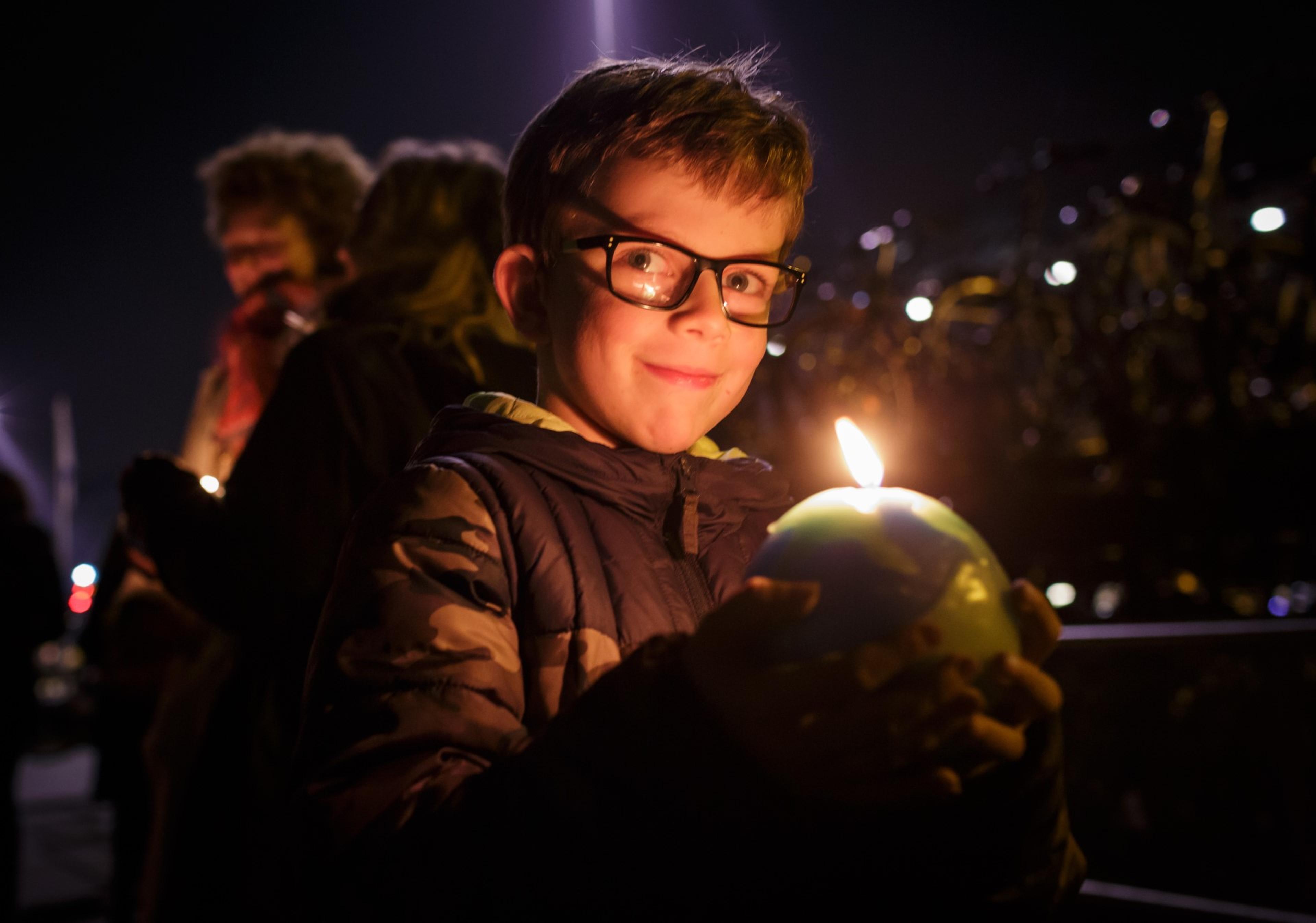 Jongen met brandende aardbol kaars in zijn handen