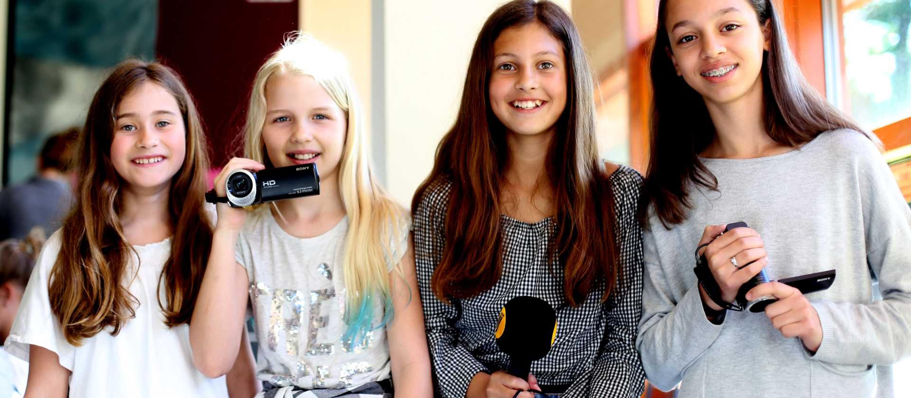 Vier meisje op een rij met videocamera