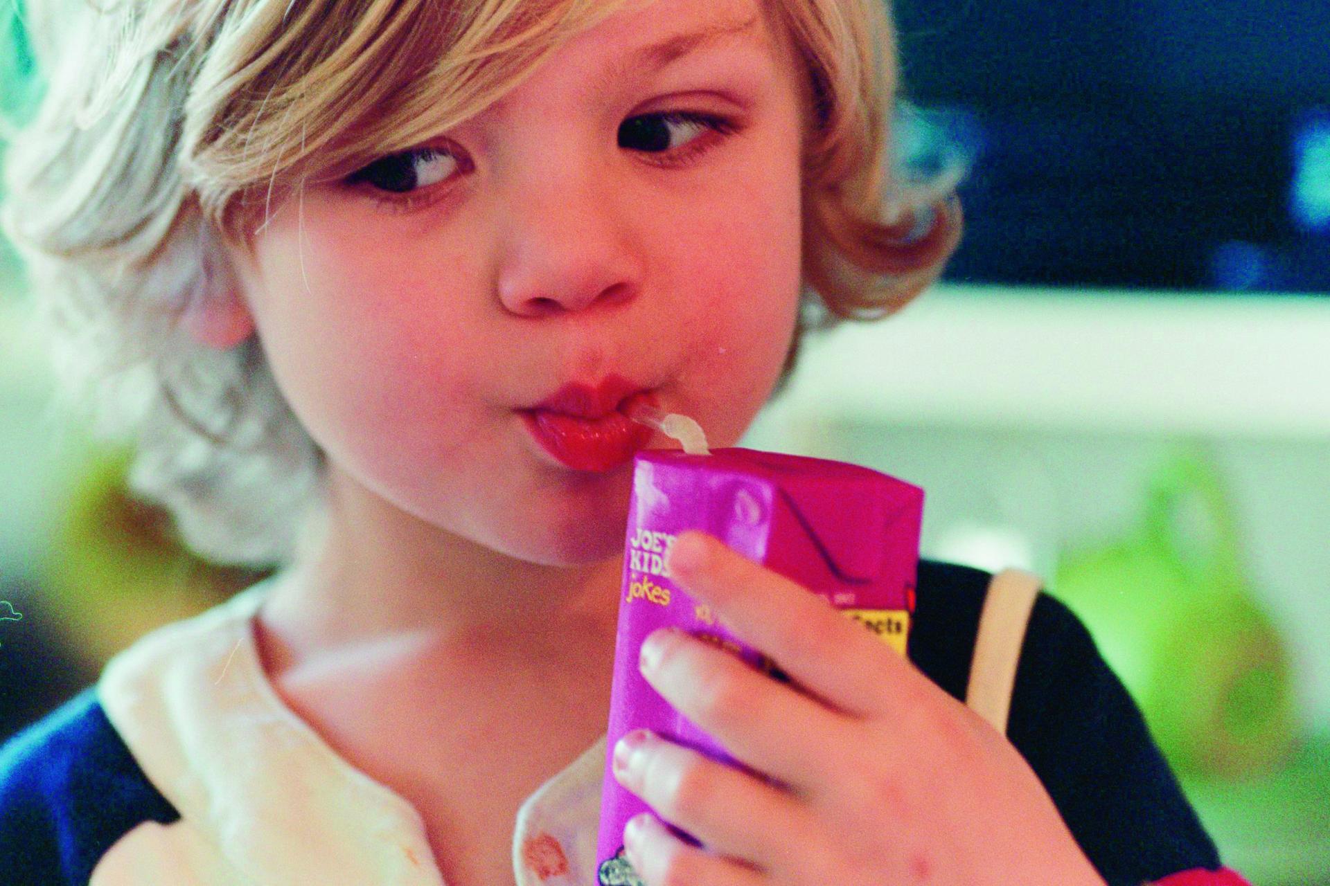Een meisje drinkt met een rietje uit een drinkpakje