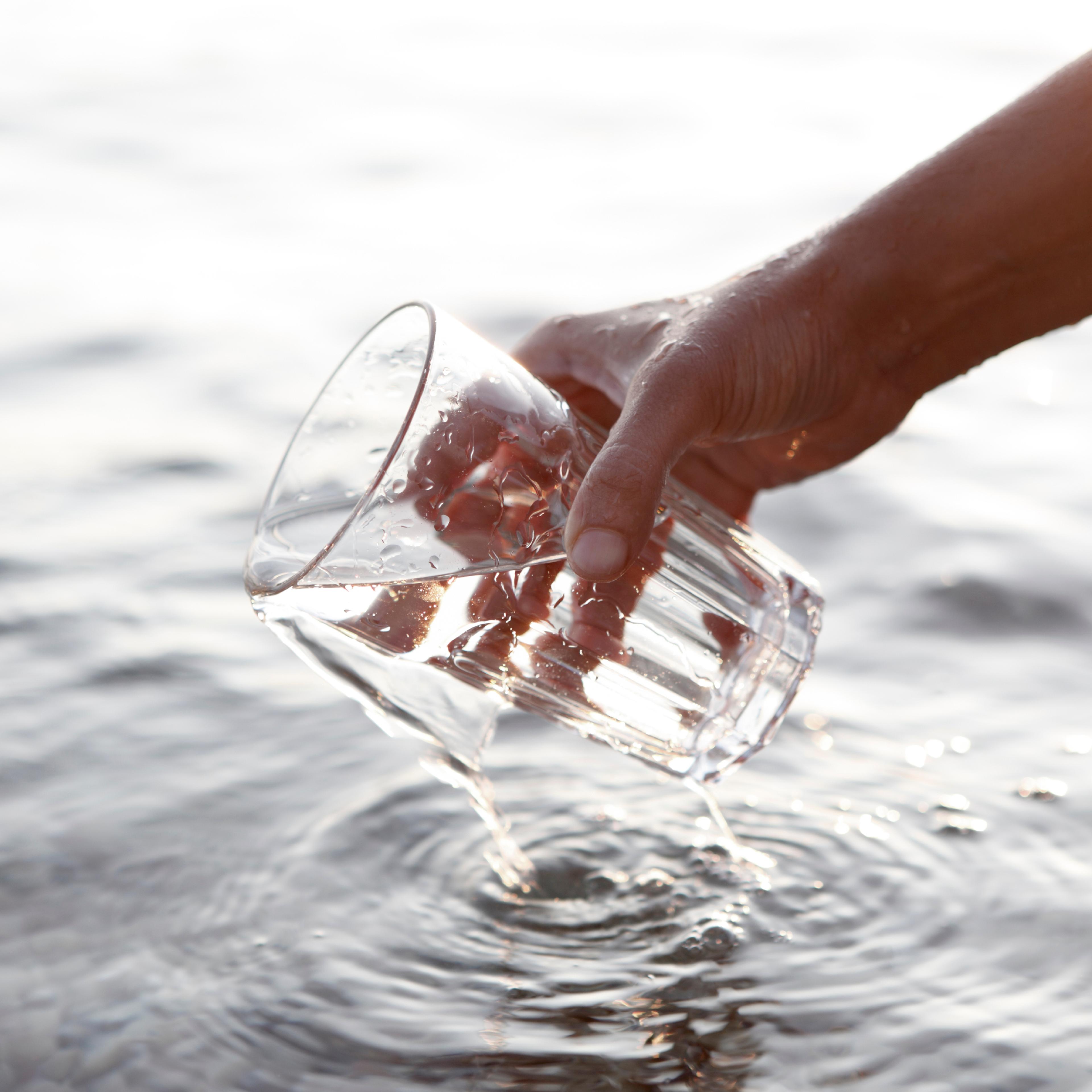 hand schept water met glas