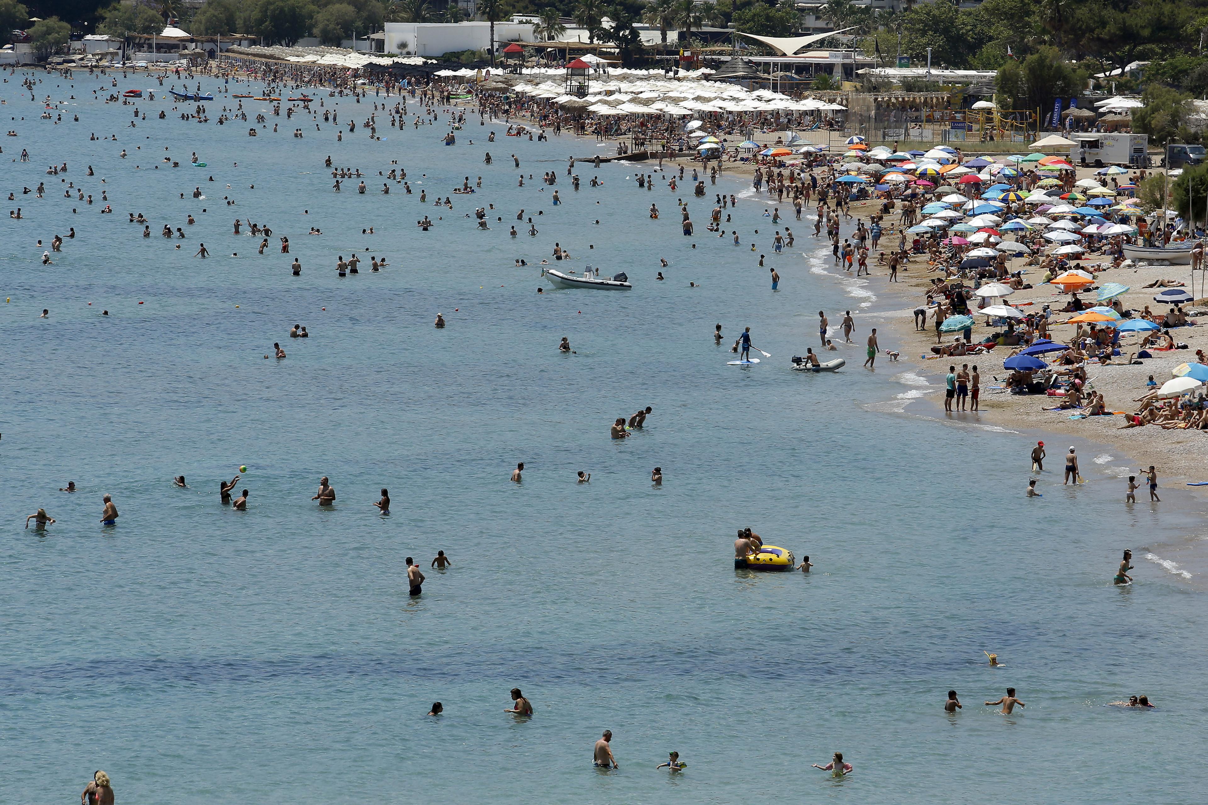 Mensen zwemmen in zee en liggen op druk bezocht strand