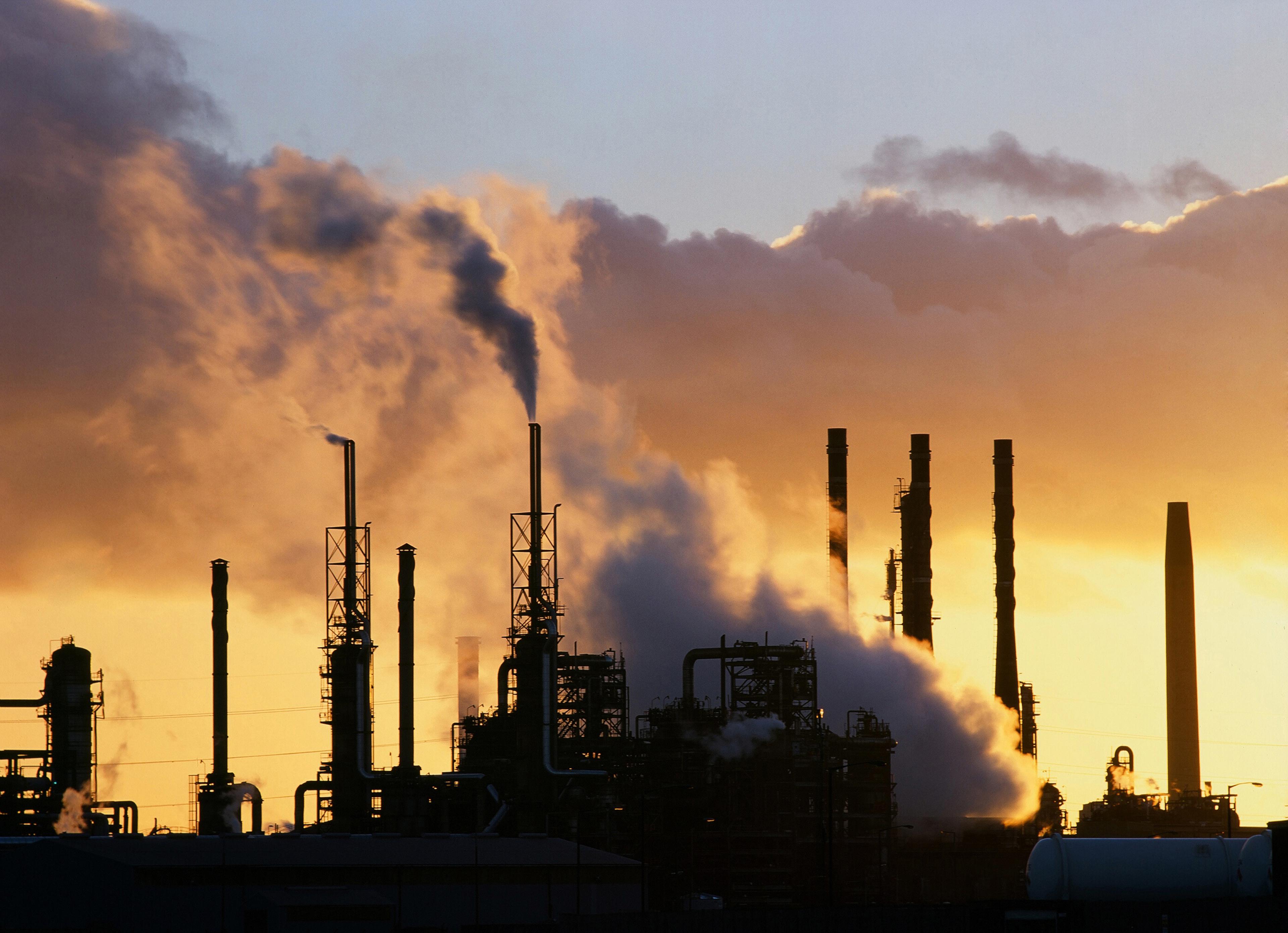 fabriek stoot gassen uit schoorstenen terwijl de zon ondergaat