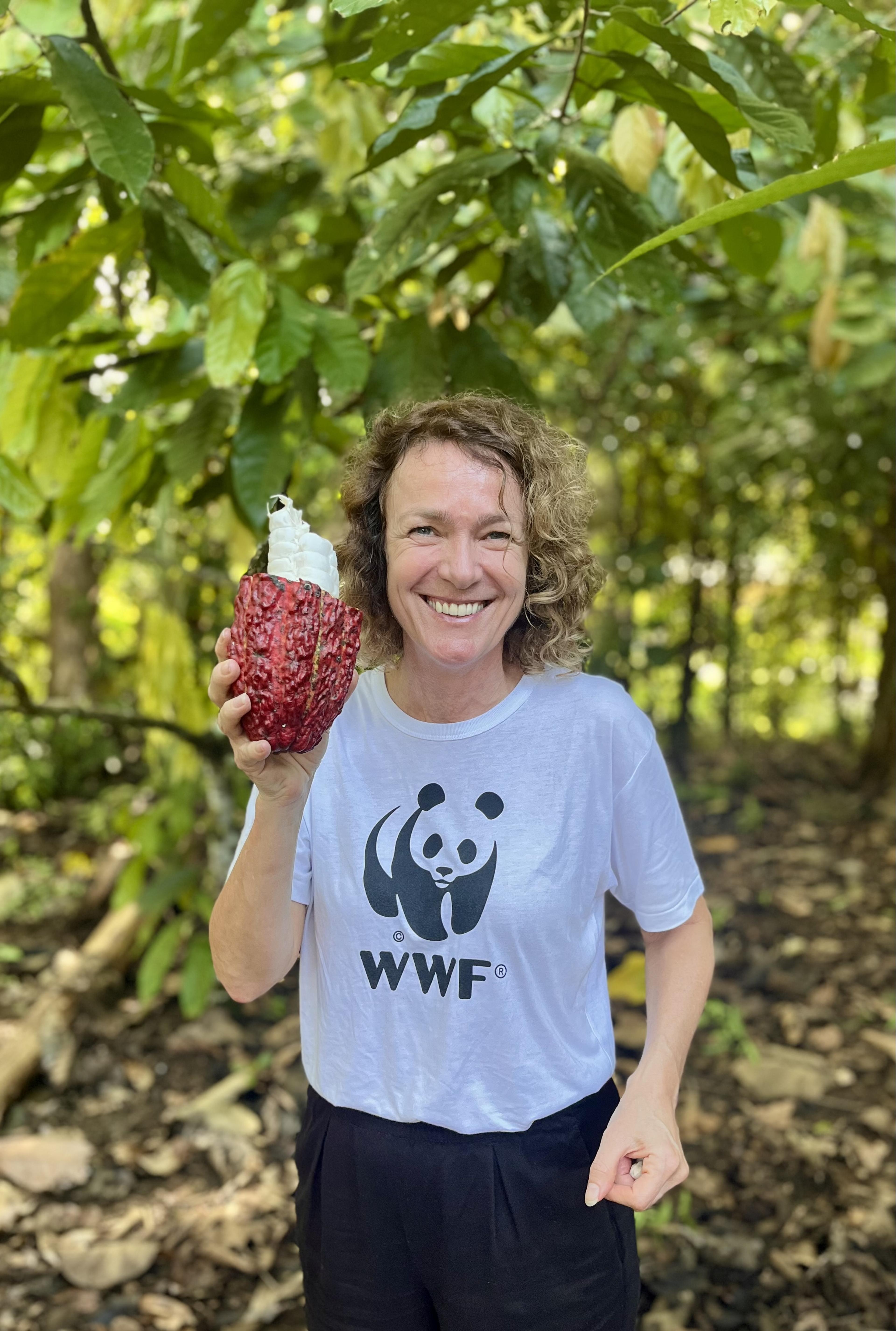 Vrouw met wit wwf tshirt houd een cacao vrucht in de lucht