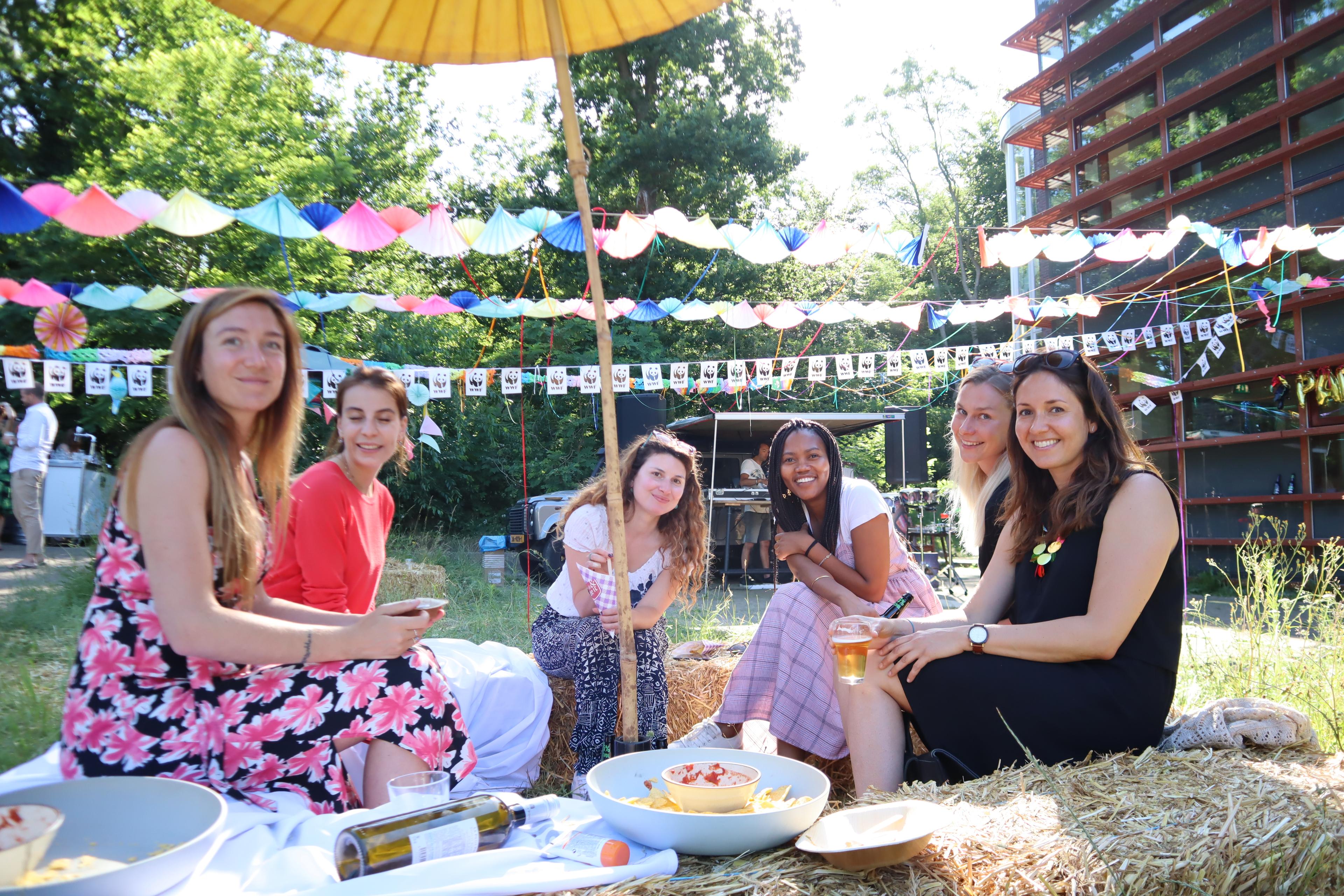 zes vrouwen zitten onder parasol op een feest