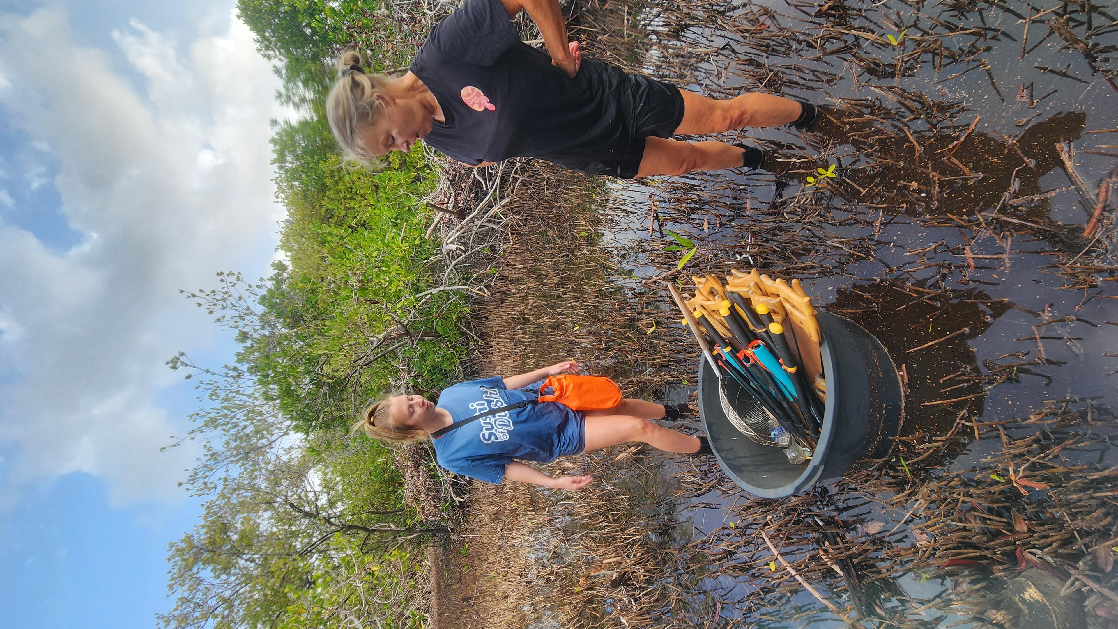 vrouwen staan bij emmer met gereedschap in mangroves