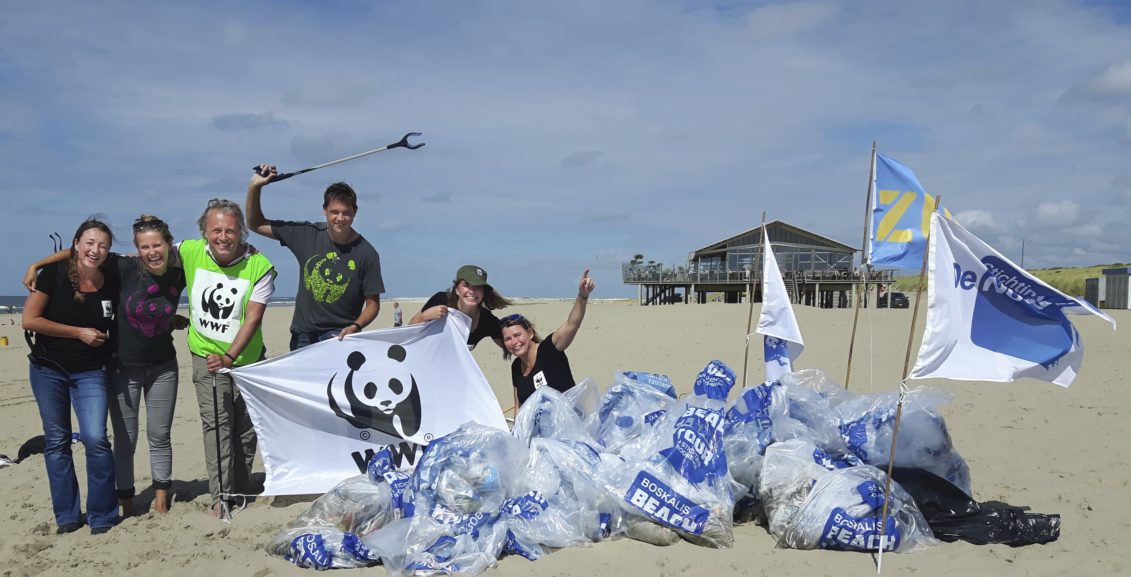 mensen met wwf logo staan naast afval op strand