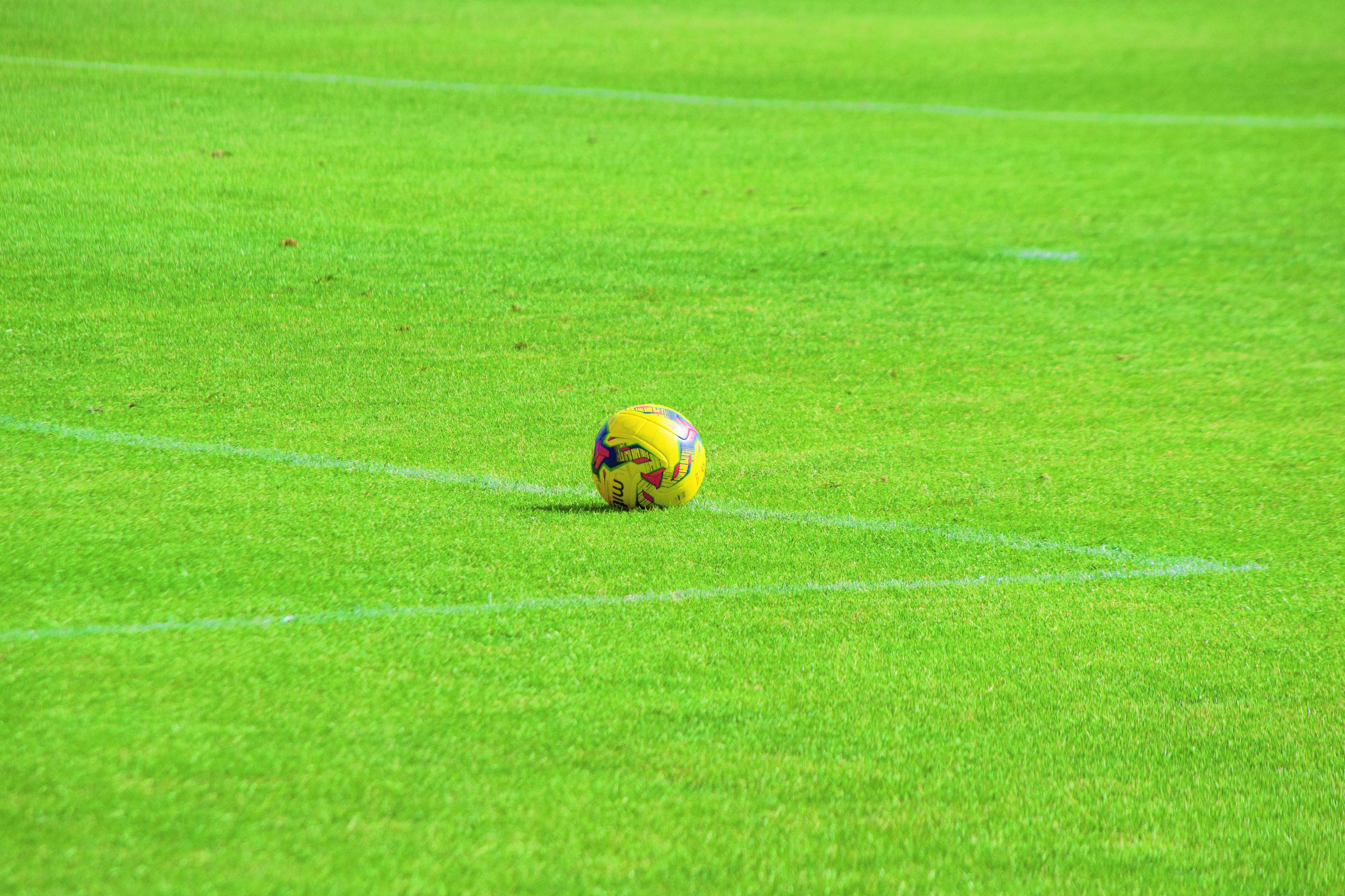Gele voetbal ligt op een voetbalveld