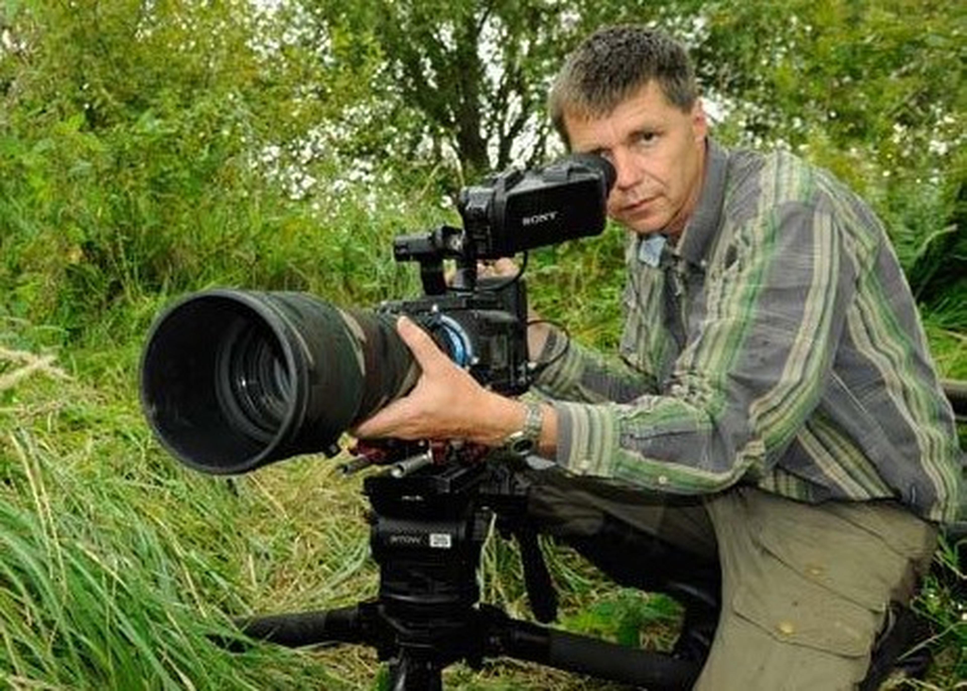 man staat achter grote lens